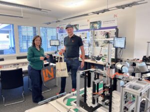 Zwei Personen stehen vor einer Industrie-4.0-Trainingsanlage von Lucas-Nülle